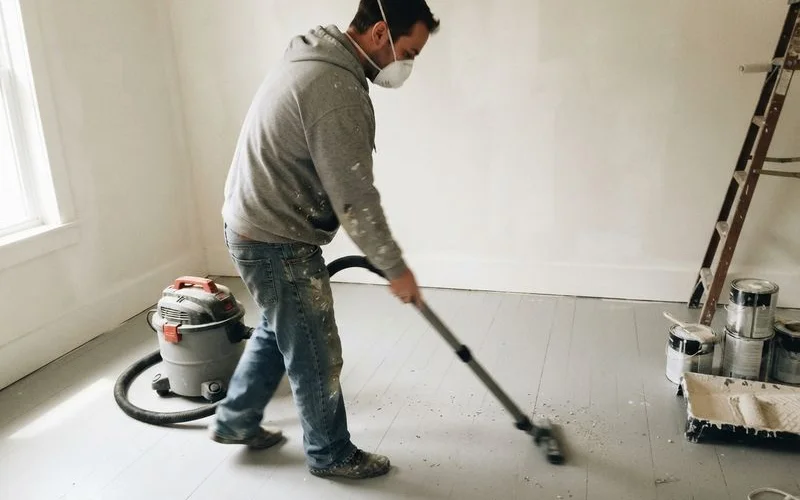 A cleaning crew wiping down cabinet surfaces and removing fine dust after a home renovation project