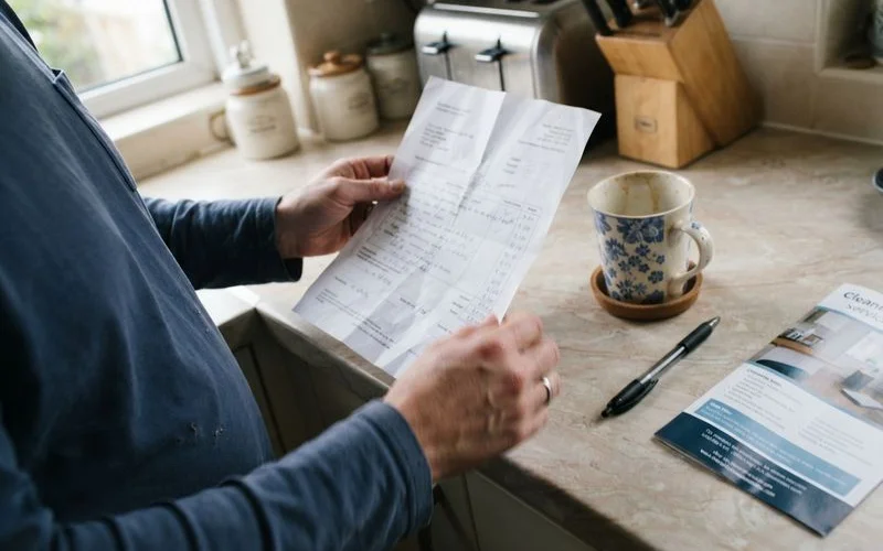 A homeowner reviewing a written cleaning service quote at a kitchen table before booking